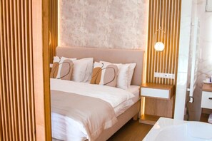 A modern bedroom with a bed, bedside table, and a wall-mounted light fixture. - M26 Prémium Apartmanház (Tihany)