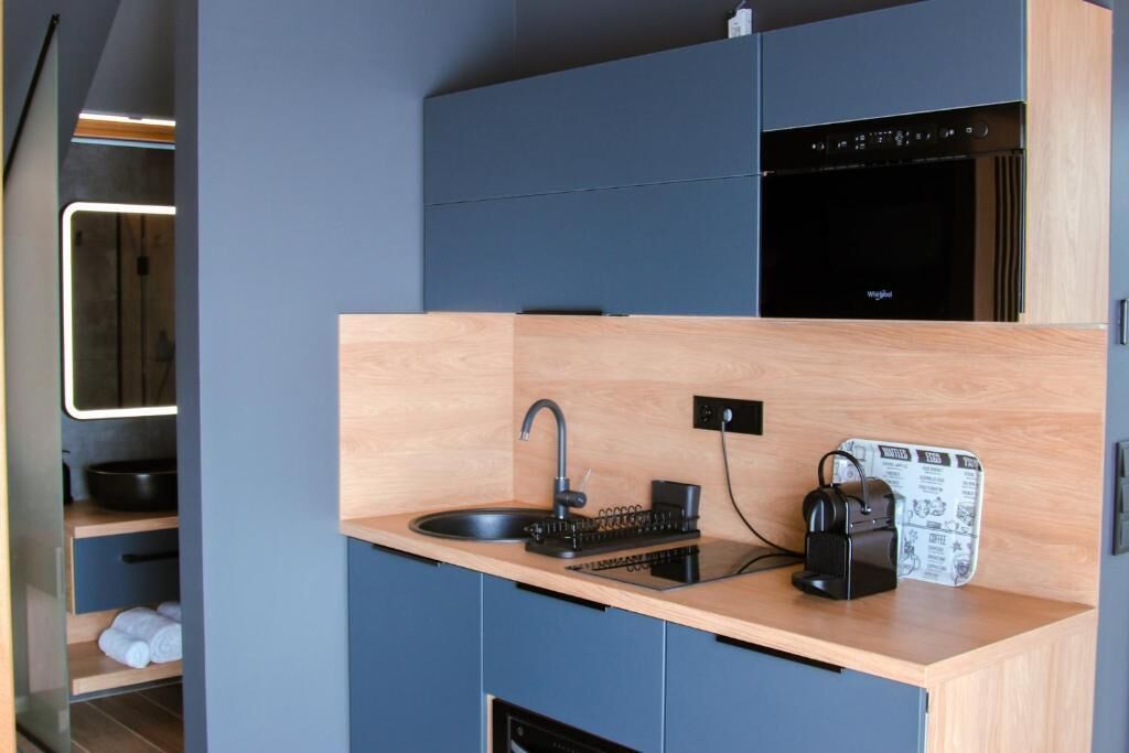 A compact kitchen with a sink, a coffee machine, and a built-in oven.