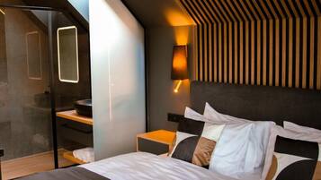A modern bedroom with a bed, bedside tables, a built-in bench, and a wall-mounted lamp.