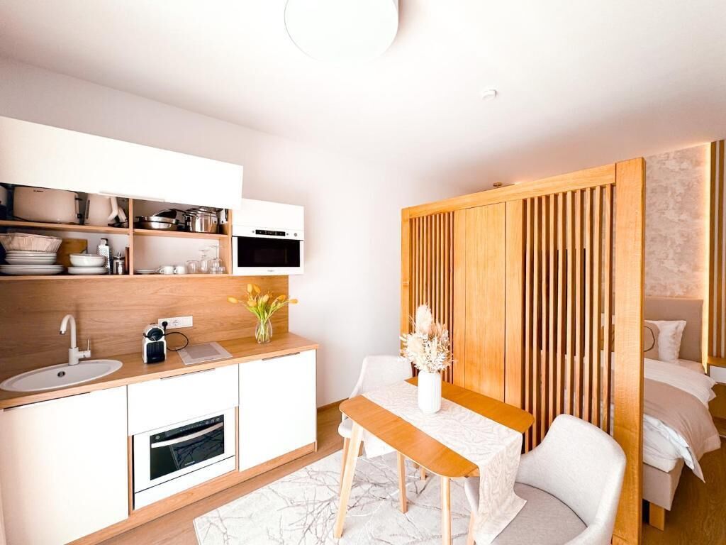 A modern kitchen with white cabinetry, a wooden countertop, and a dining area with a table and chairs.
