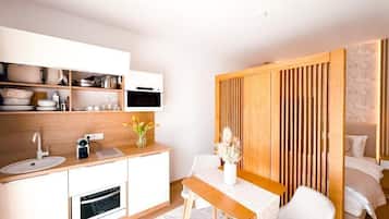 A modern kitchen with white cabinetry, a wooden countertop, and a dining area with a table and chairs.