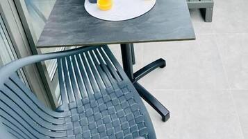 Un balcon avec une table, des chaises, un jacuzzi et une porte vitrée.
