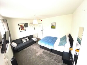 A hotel room with a bed, a sofa, a desk, and a mirror. - Crown House Kings Cross Flat 2 / Sleeps up to 8 (London)