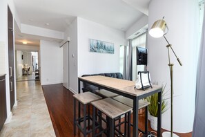 A modern dining area with a wooden table and chairs, a floor lamp, and a potted plant. - Westmere Suites (Toronto)