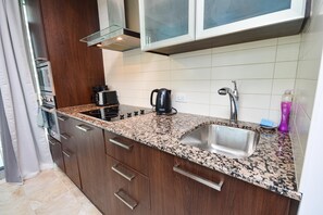 A kitchen with granite countertops, stainless steel sink, and wooden cabinets. - Westmere Suites (Toronto)