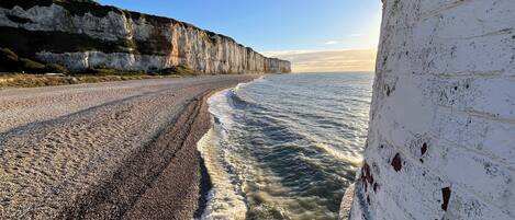 A coastal road with a white wall on the right and cliffs on the left.