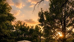 A geodesic dome tent with a bed inside, a wooden deck, and a table with a bench.