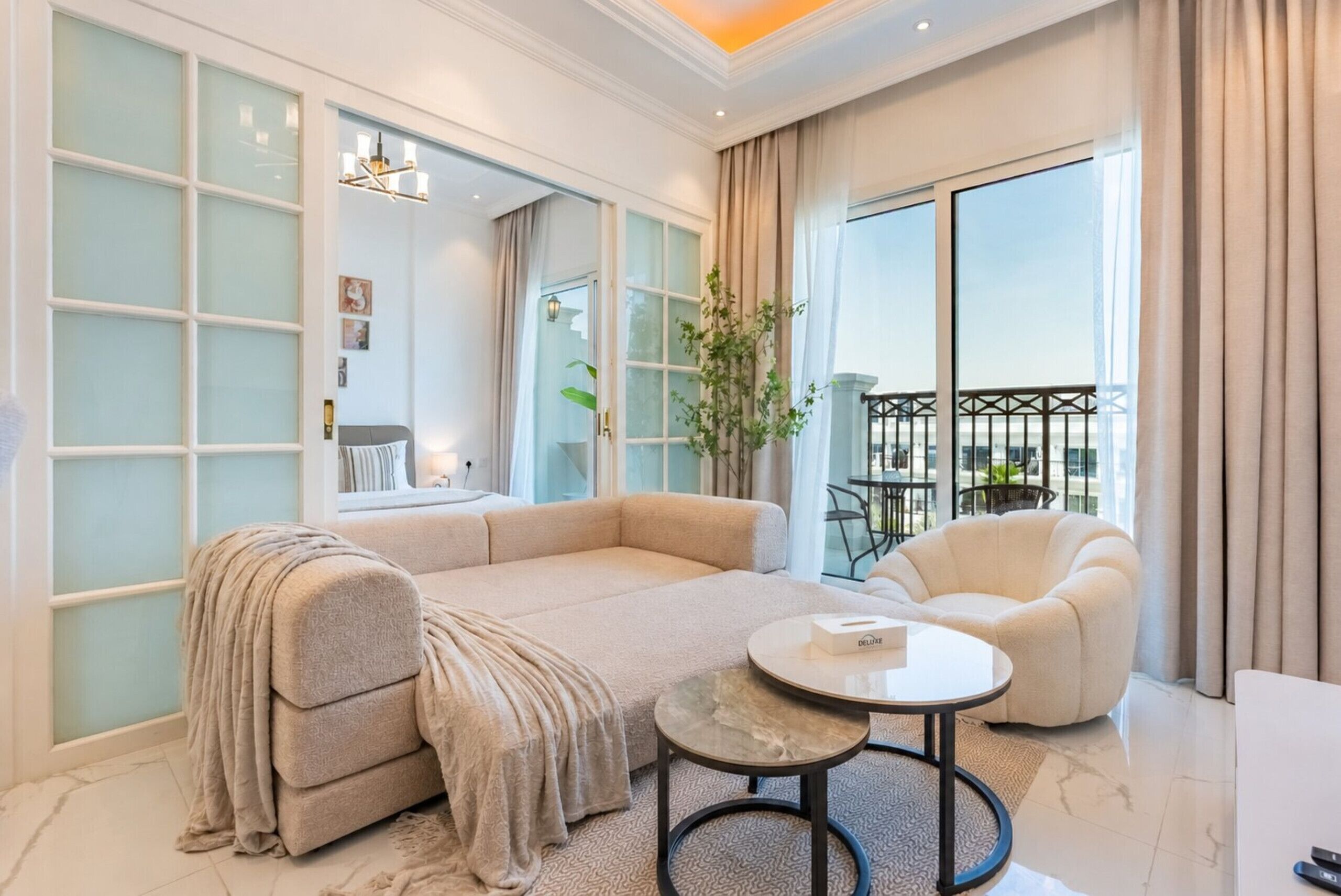 A modern living room with a sofa, a round coffee table, a chair, and a balcony with a view.