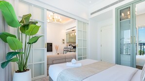 Ein modernes Schlafzimmer mit einem großen Bett, einer Topfpflanze, einer Couch und Blick auf die Stadt.
