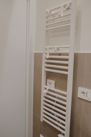 A bathroom with a white towel rack, beige tiles, and a visible electrical outlet. - NAUSICAA: Your Sardinia vacation begins in Cagliari (Cagliari)
