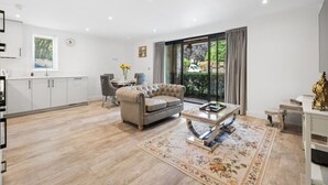 A modern living room with a sofa, coffee table, and a dining area with chairs. - Calm, Modern Flat with Terrace Near Station - Pass the Keys (Hemel Hempstead)