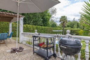 A patio with a grill, a table with chairs, and a pergola. - Cabañita rústica con piscinas cerca de A Coruña (Peiraio)