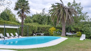 A swimming pool with lounge chairs, a table, and a hammock. - Acogedor chalet rústico con piscinas, Wi-Fi y aire acondicionado (Peiraio)