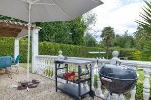 Ein Patio mit Grill, einem Holzwagen und Gartenmöbeln.