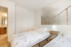 Ein Schlafzimmer mit Bett, Nachttisch, Lampe und einem Wandbild.