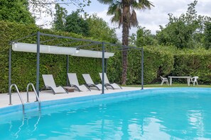 Ein Swimmingpool mit Liegestühlen und einer überdachten Sitzgruppe.