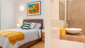 A bedroom with a bed, pillows, a bedside table, and a wall-mounted painting.