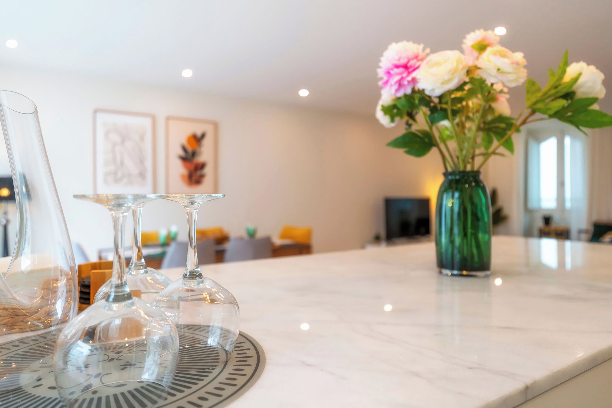 Uma mesa de jantar com copos de vidro transparente e um vaso de flores.
