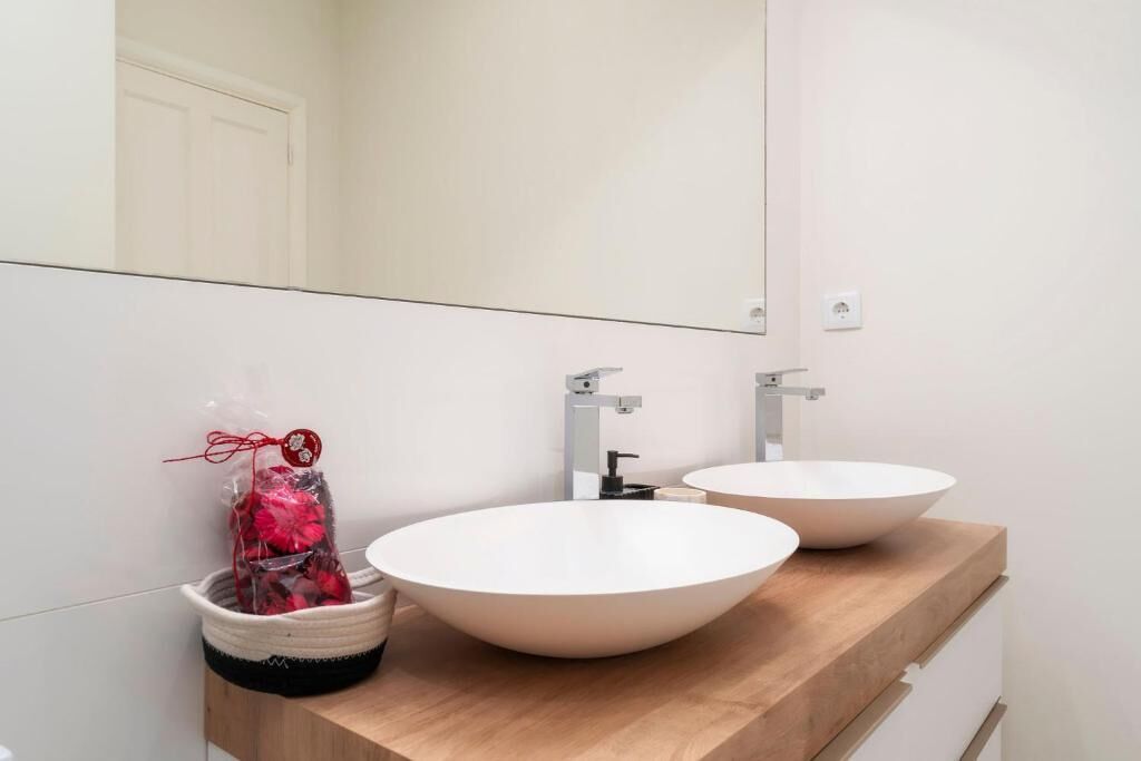 A bathroom with two white sinks, a mirror, and a towel rack.