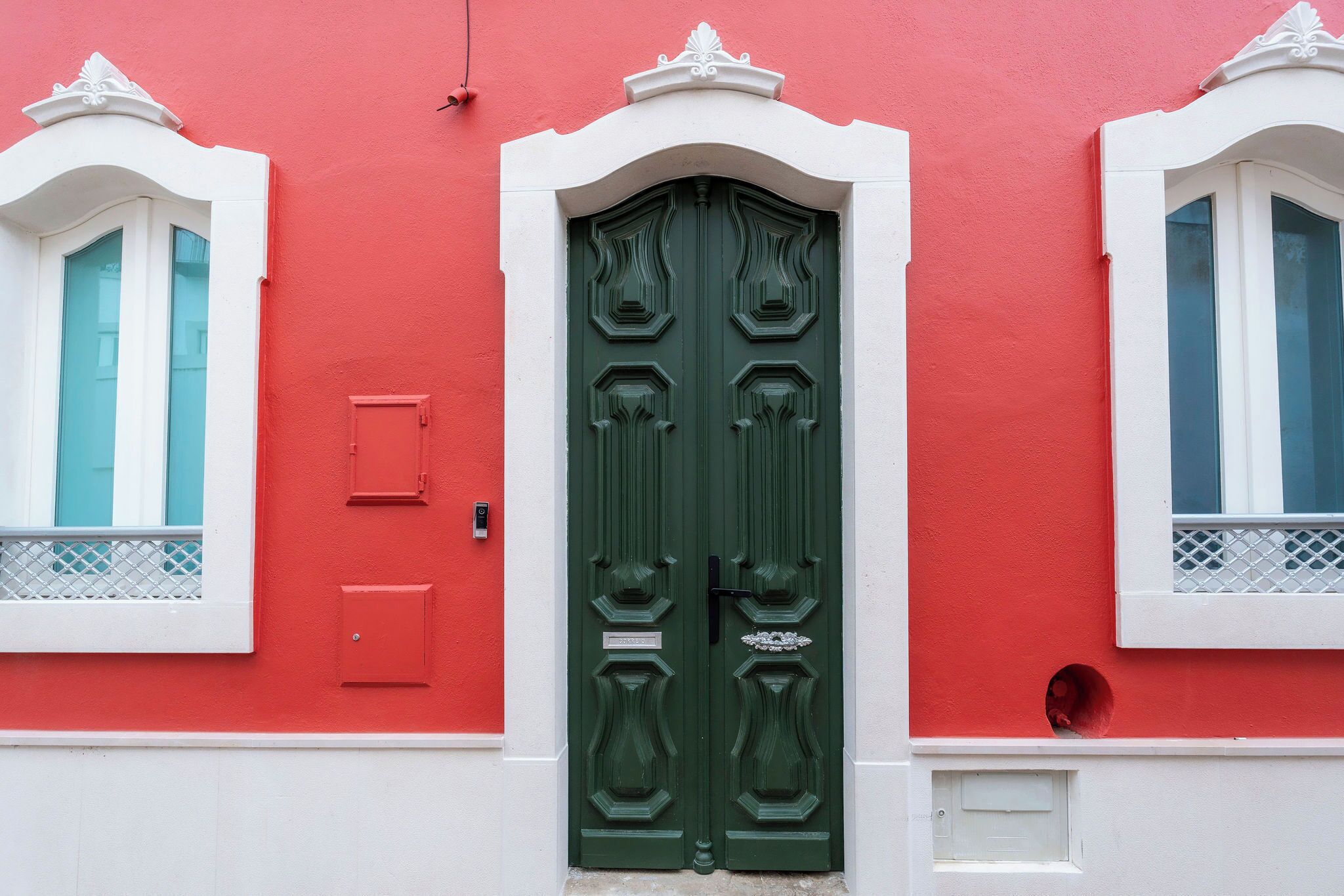 A building with a green door, white trim, and red walls.