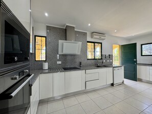 Een moderne keuken met een inbouwfornuis, een spoelbak en een raam met decoratieve ijzeren spijlen.