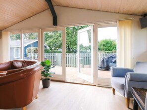 A covered patio with a brown leather chair, a grey armchair, and a wooden table. - 4 Star Holiday Home in Vaeggerlose (Vaeggerlose)