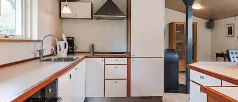 A kitchen with wooden cabinets, a built-in oven, a coffee maker, and a sink.