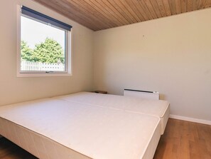 A room with a single bed, a window with a view of trees, and a white radiator. - 4 Star Holiday Home in Vaeggerlose (Vaeggerlose)