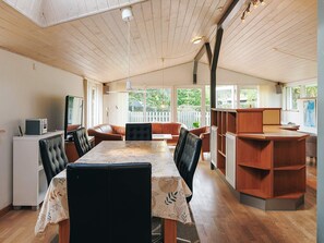 A spacious room with a wooden ceiling, a dining table with chairs, a sofa, and a small desk with a computer. - 4 Star Holiday Home in Vaeggerlose (Vaeggerlose)