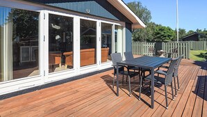 Una terrazza con tavolo e sedie, una porta scorrevole in vetro e un giardino recintato.