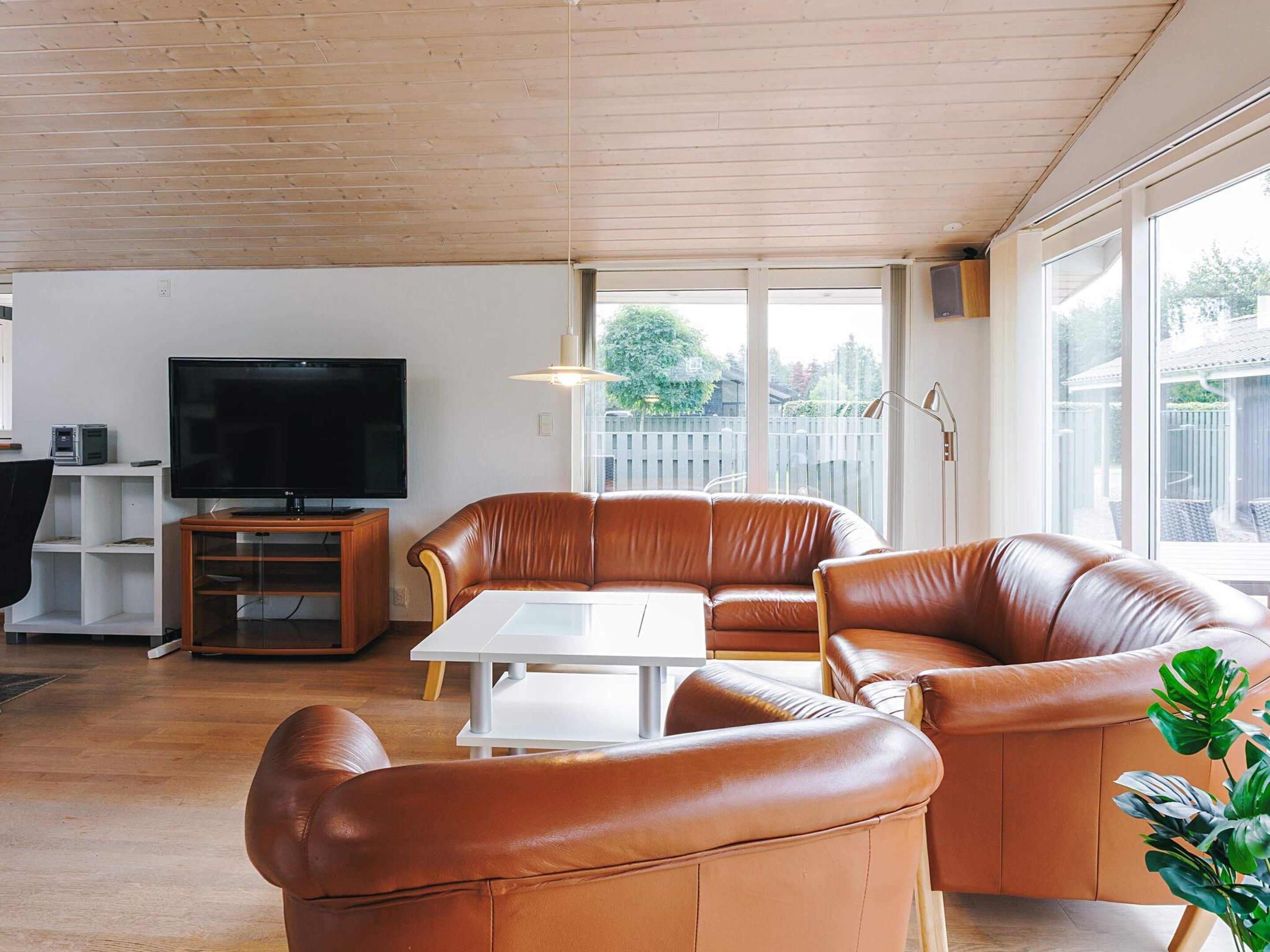A living room with a leather sofa, a television, and a dining table.