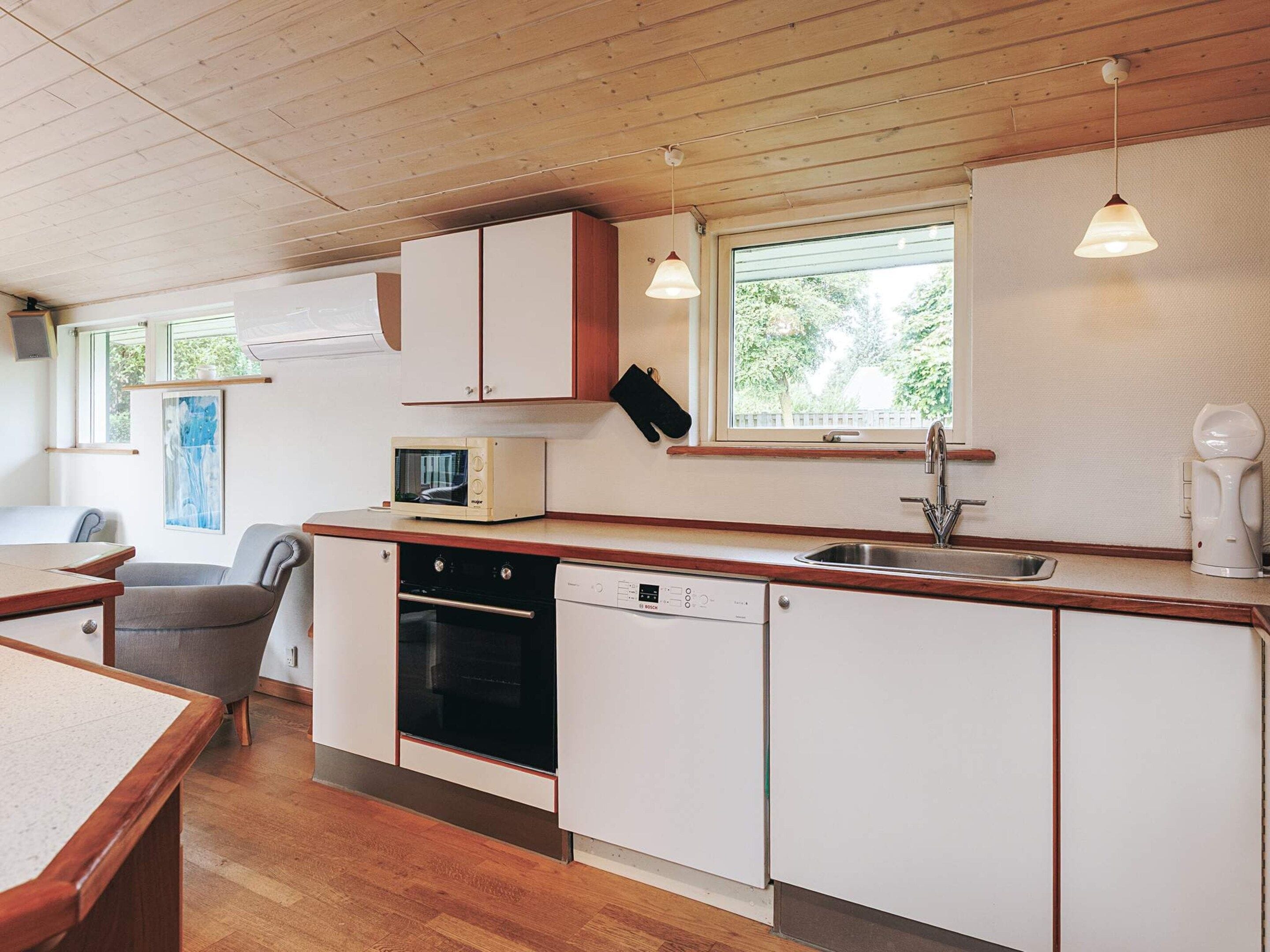 A compact kitchen with wooden cabinets, a microwave, a dishwasher, and a sink.