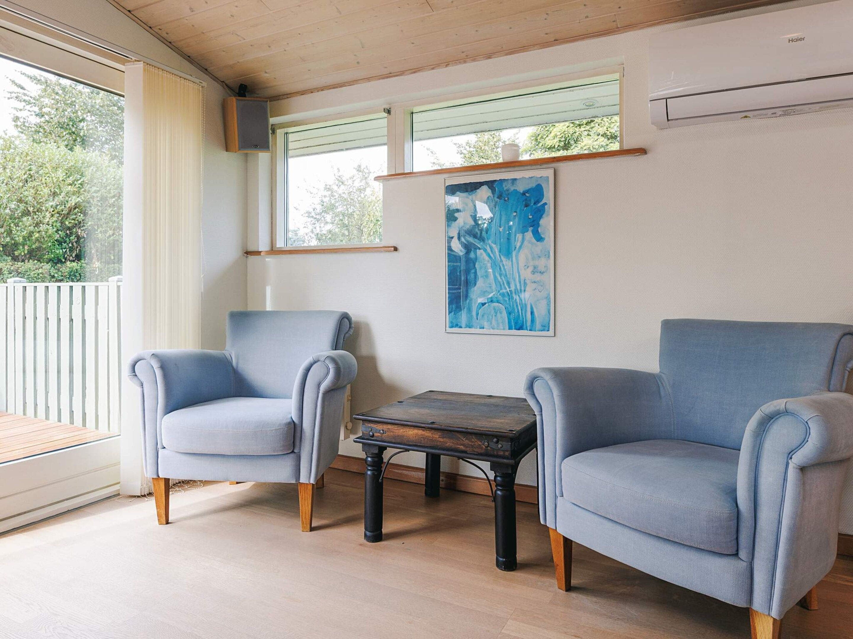 A room with two armchairs, a small table, and a window with a view of greenery.