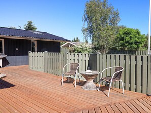 A wooden deck with two wicker chairs and a small table, surrounded by a wooden fence. - 4 Star Holiday Home in Vaeggerlose (Vaeggerlose)