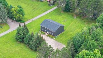 A house with a dark roof, surrounded by a well-maintained lawn and dense trees.