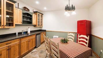 A kitchen with wooden cabinets, a dining table with chairs, and a red refrigerator.