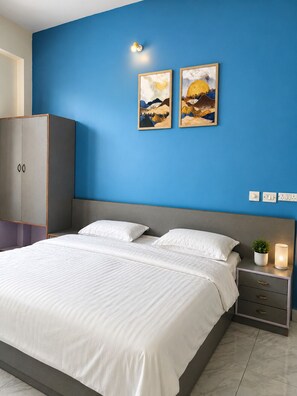 A bedroom with a bed, nightstands, a wardrobe, and two wall-mounted paintings.