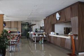 A hotel lobby with a reception desk, seating area, and a large clock on the wall. - Btc Hotel Bandung (Bandung)