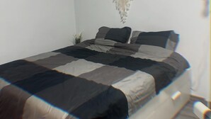 Un dormitorio con cama, un tapiz de macramé y una planta pequeña.