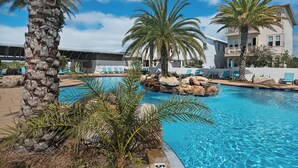 A swimming pool with palm trees and lounge chairs, surrounded by a building with balconies. - 🌴 Gulfview on 30A | Resort Pool, Great Amenities & Beach Access🏖️ (Santa Rosa Beach)
