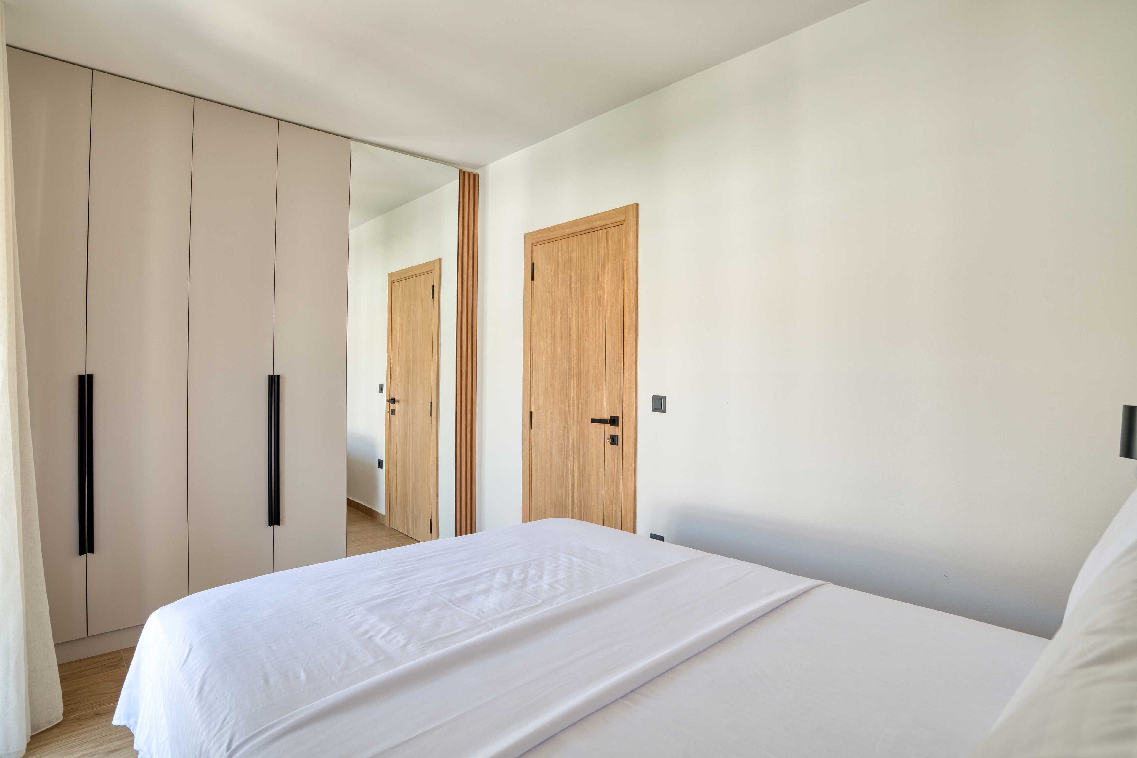 A bedroom with a bed, a wardrobe, and a door.
