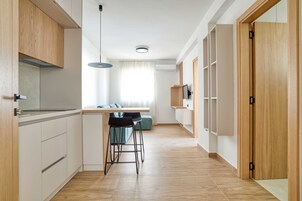 Una cocina moderna con armarios de madera, un comedor con mesa y sillas, y un pasillo que conduce a una habitación con puerta.