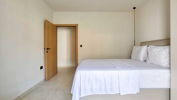 A bedroom with a bed, a door, and a light fixture.