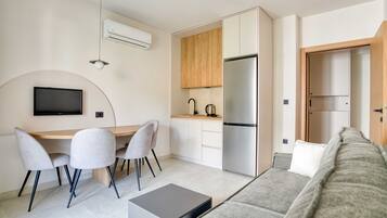 A compact living space with a kitchenette, a dining area, a sofa, and a flat-screen TV.