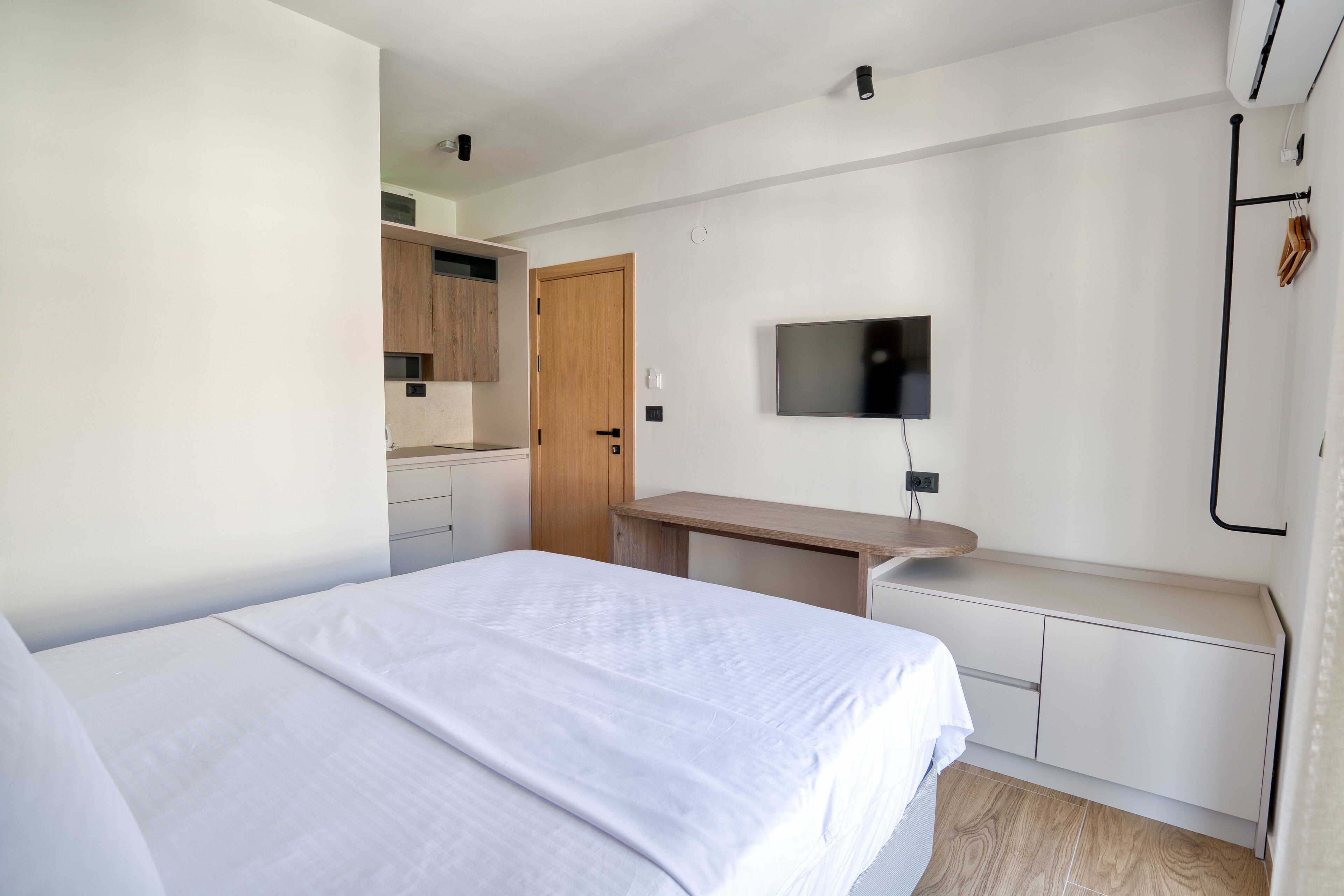 A hotel room with a bed, a desk, a television, and a wardrobe.