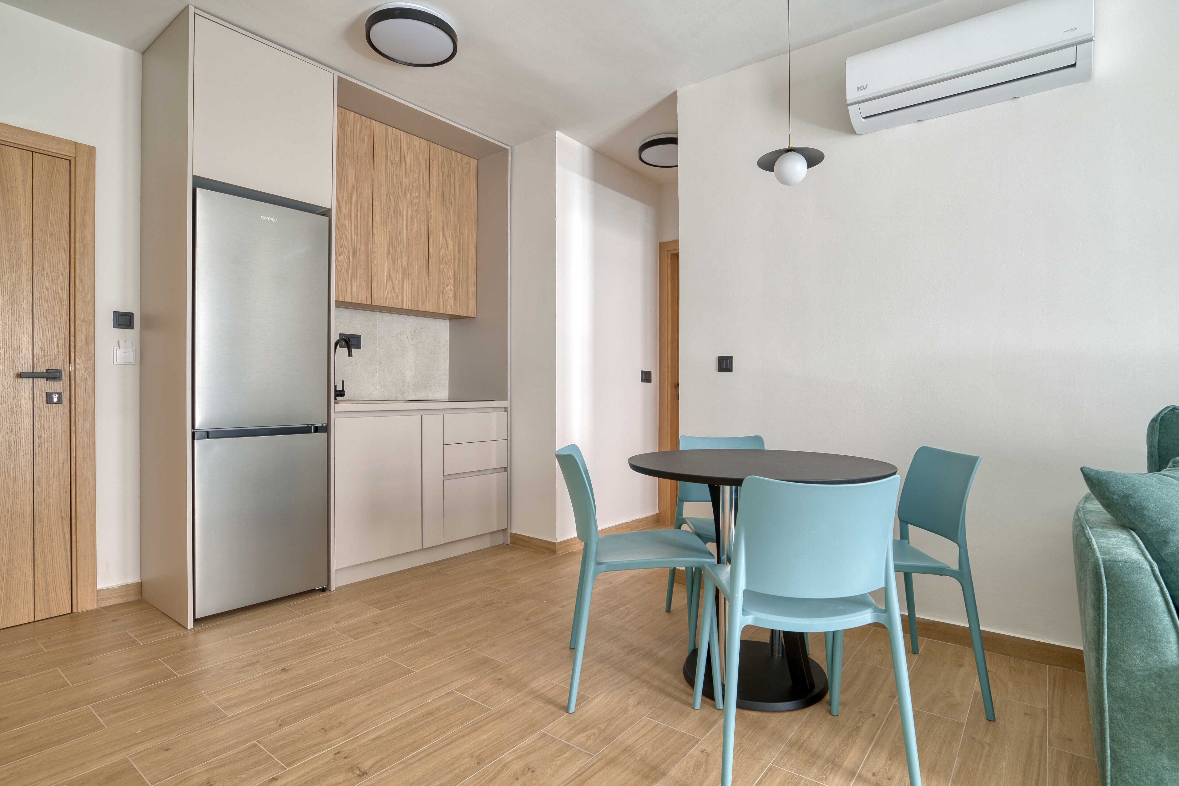 Une cuisine moderne équipée d’un réfrigérateur, de placards et d’un coin repas avec des chaises et une table.
