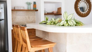 A kitchen with a white countertop, wooden chairs, a refrigerator, and a mirror. - Casa Melissa 2BR Pool Villa by TVM (Ubud)