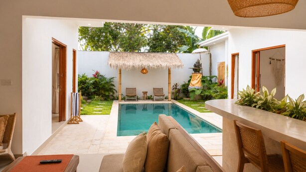 A poolside area with a thatched roof, outdoor seating, and a view of the pool. - Casa Melissa 2BR Pool Villa by TVM (Ubud)