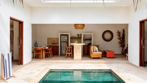A spacious indoor pool area with a kitchen and seating area in the background. - Casa Melissa 2BR Pool Villa by TVM (Ubud)