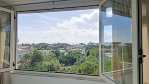 Une fenêtre donnant sur un paysage urbain, avec des bâtiments et des arbres.